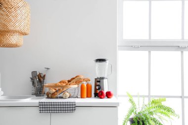 Taze ekmek, elma, meyve suyu ve blender dolu beyaz mutfak tezgahı