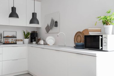 Mikrodalga fırını, lavabosu ve çatalı olan beyaz mutfak tezgahları.