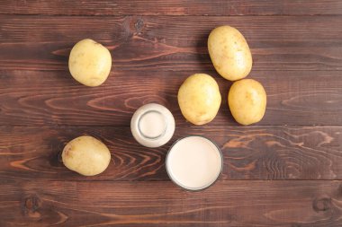 Ahşap zeminde bir şişe ve bir bardak lezzetli patates sütü.