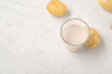 Hafif arka planda bir bardak lezzetli patates sütü.