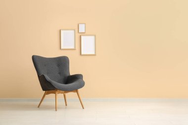 Şık siyah koltuk ve bej duvarın yanındaki çerçeveler.