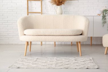 Tuğla duvarın yanında halı olan rahat beyaz kanepe.