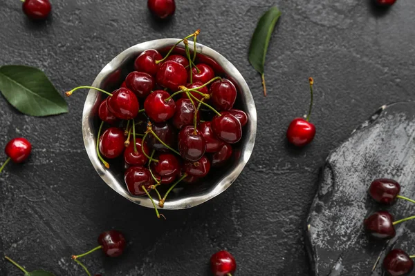 stock image Bowl and board with sweet cherries on black background