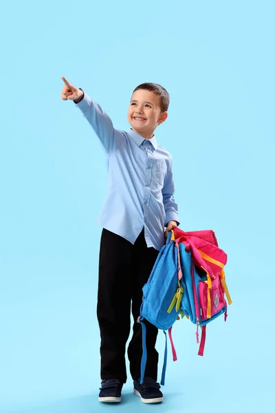Kleiner Schuljunge Mit Rucksack Zeigt Auf Etwas Auf Hellblauem Hintergrund — Stockfoto