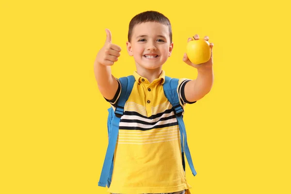 Mały Uczeń Jabłkiem Pokazujący Kciuk Góry Żółtym Tle — Zdjęcie stockowe