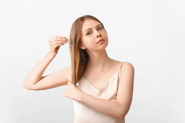 Młoda Kobieta Stosująca Olejek Kosmetyczny Pielęgnacji Włosów Jasnym Tle — Zdjęcie stockowe