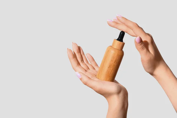 Hafif Arka Planda Kozmetik Yağı Şişesi Olan Bir Kadının Elleri — Stok fotoğraf