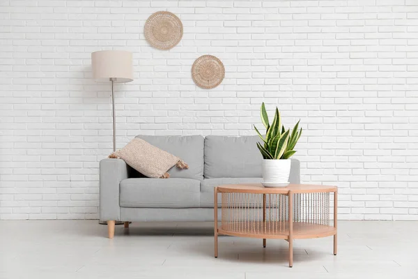 白いレンガの壁の近くのソファ テーブルと観葉植物とリビングルームのインテリア — ストック写真