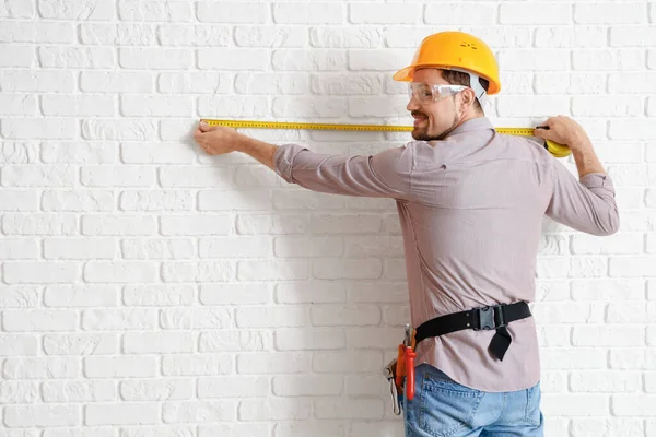 Construtor Masculino Medindo Parede Tijolo Branco — Fotografia de Stock