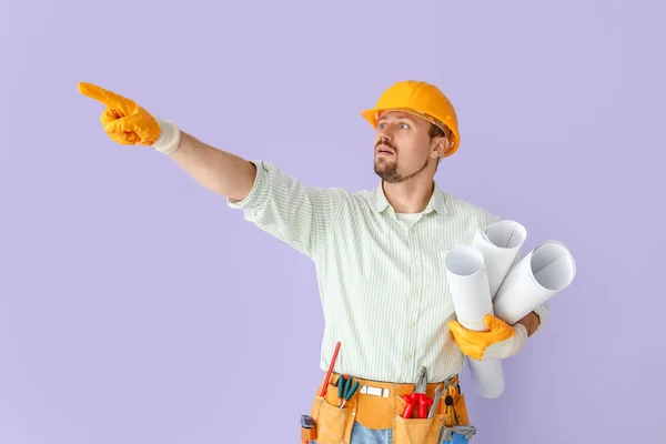 Constructor Masculino Con Planos Casa Apuntando Algo Sobre Fondo Lila — Foto de Stock