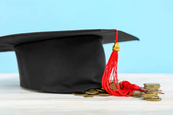 Chapéu Graduação Pilha Moedas Mesa Branca Contra Fundo Azul Conceito — Fotografia de Stock
