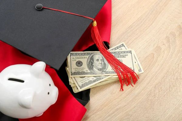 ピギーバンク ドル紙幣 卒業キャップと木製の背景にガウン 学生ローンの概念 — ストック写真