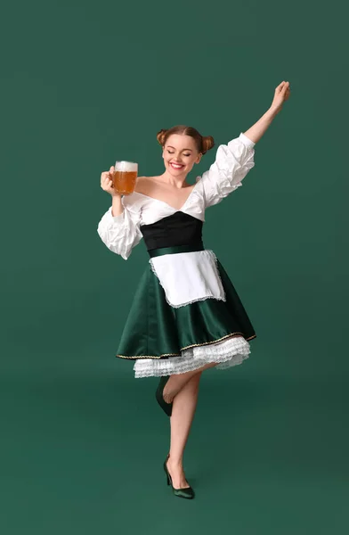 美丽的十月节侍应生 带着啤酒在绿色背景下跳舞 — 图库照片