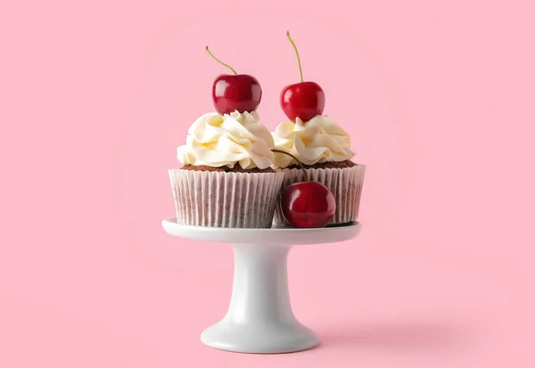 stock image Stand with tasty cherry cupcakes on pink background