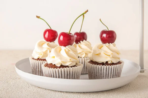 stock image Plate with tasty cherry cupcakes on light background