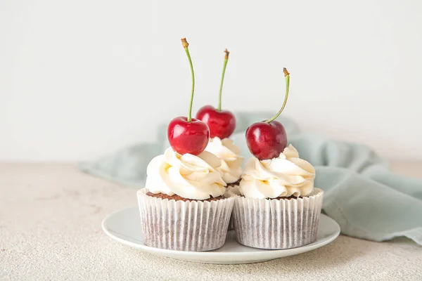 stock image Plate with tasty cherry cupcakes on light background