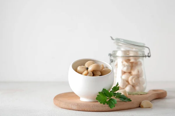 stock image Bowl with canned mushrooms on light background