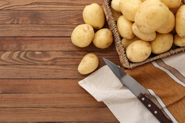 Stock image Wicker box with raw potatoes on wooden background