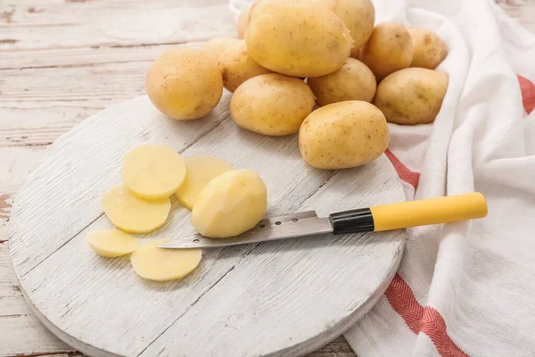 Brett Mit Rohen Kartoffeln Und Scheiben Auf Weißem Holzgrund — Stockfoto