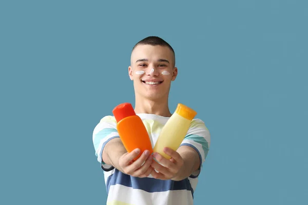 Vrolijke Jongeman Met Flessen Zonnebrandcrème Blauwe Achtergrond — Stockfoto