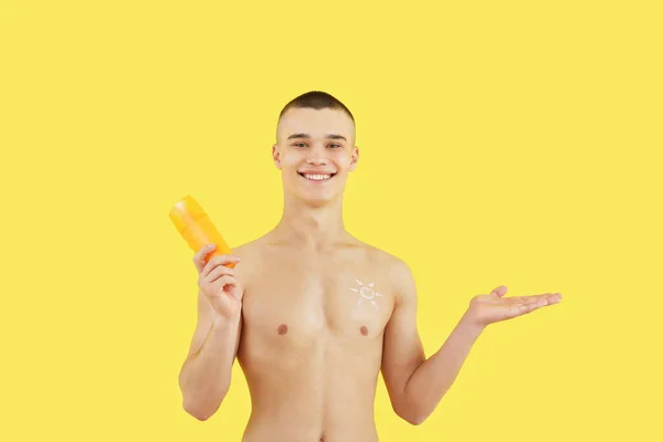 Happy Young Man Bottle Sunscreen Cream Pointing Something Yellow Background — Stock Photo, Image