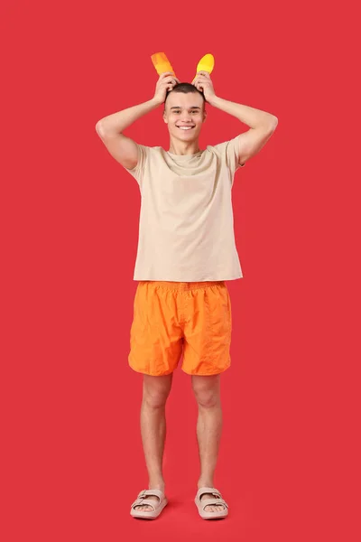 Happy Young Man Bottles Sunscreen Cream Red Background — Stock Photo, Image