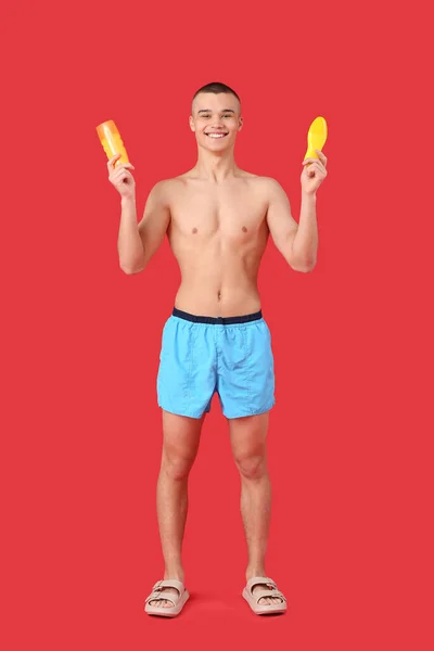 Happy Young Man Bottles Sunscreen Cream Red Background — Stock Photo, Image