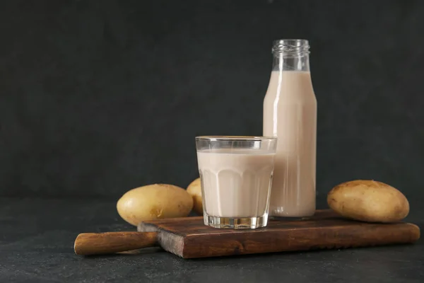 stock image Bottle and glass of tasty potato milk on black background