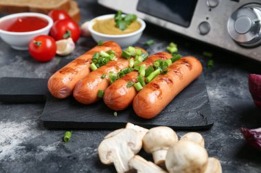 Izgara sosis ve siyah grunge masasında sebzeli tahta.