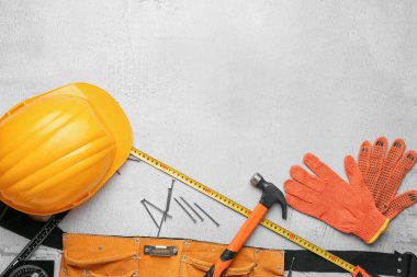 Çekiçli, kasklı, eldivenli ve gri arka planda çivili alet kemeri. İşçi Bayramı kutlamaları