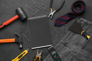 Not defteri, farklı aletler, tırnaklar, kravat ve siyah grunge arka plan kot. İşçi Bayramı kutlamaları