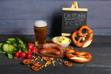 Bir bardak soğuk bira, üzerinde kelime yazan karatahta OKTOBERFEST ve farklı atıştırmalıklar.