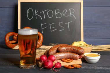 Bir bardak soğuk bira, üzerinde kelime yazan karatahta OKTOBERFEST ve farklı atıştırmalıklar.