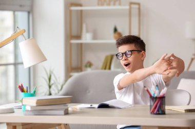 Yorgun küçük çocuk evde ders alıyor.