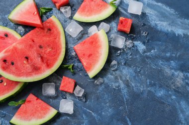 Mavi zemin üzerinde naneli ve buz küplü taze karpuz parçaları.