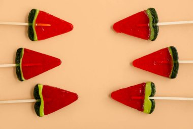 Bej arka planda karpuz dilimi şeklinde lolipoplar