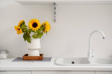 Mutfak tezgahında güzel ayçiçekleri olan vazo.