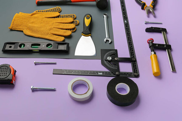 Композиция с различными инструментами на сиреневом фоне. Празднование Дня труда