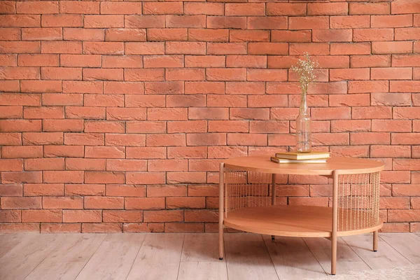 Kahverengi Tuğla Duvarın Yanında Kitap Vazo Olan Ahşap Bir Sehpa — Stok fotoğraf