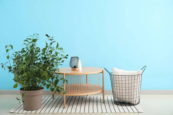 Stolik Kawowy Lampą Rośliną Domową Poduszką Koszyku Przy Niebieskiej Ścianie — Zdjęcie stockowe