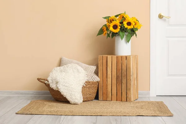 在米色墙边的柳条篮里 放上美丽的向日葵和木制的盒子和垫子 — 图库照片
