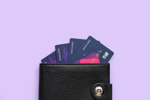 Black leather wallet with credit cards on lilac background