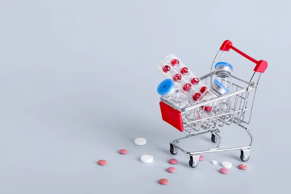 Mini Einkaufswagen Mit Verschiedenen Pillen Auf Grauem Hintergrund — Stockfoto