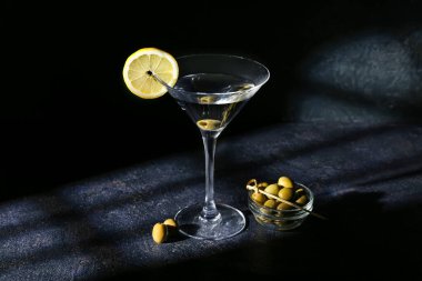 Limonlu martini ve koyu arkaplanda yeşil zeytin.