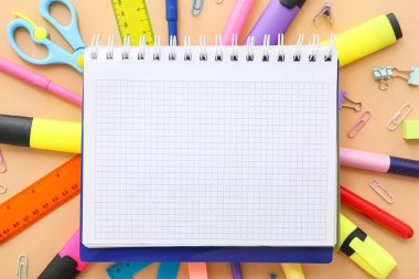 Çerçeve bej arkaplanda boş defter ile farklı kırtasiyeden yapılmıştır