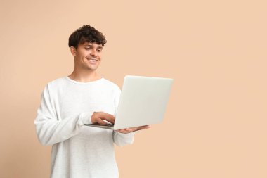 Erkek programcı bej arka planda dizüstü bilgisayarla çalışıyor