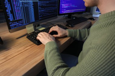 Geceleri ofiste bilgisayarla çalışan erkek programcı, yakın plan.