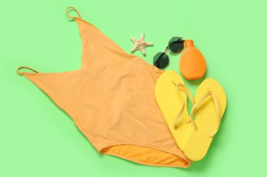 Parlak mayo, parmak arası terlik, güneş gözlüğü, bir şişe güneş kremi ve arka planda deniz yıldızı.