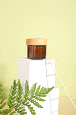 Alçı podyumlu kompozisyon, kozmetik ürün kavanozu, eğrelti otu yaprağı ve renk arkaplanına dekoratif merdiven