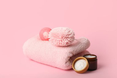 Temiz havlu, banyo bombası, sünger ve krem pembe arka planda.